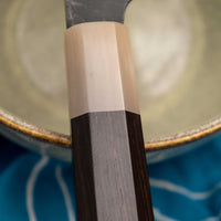 Yoshida Bunka SUJ-2 Kuro-uchi 190 mm ročno izdelan kuhinjski nož iz serije Yoshida Hamono, s trpežnim SUJ-2 jeklom, rustikalnim kuro-uchi zaključkom, ročajem iz ebenovine ter unikatno gravuro koi krapa, idealen za raznolika kuhinjska opravila in kot darilo.