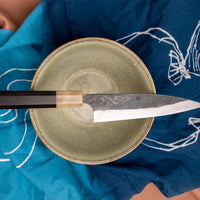 Yoshida Petty SUJ-2 Kuro-uchi 145 mm ročno izdelan kuhinjski nož s trpežnim SUJ-2 jeklom, rustikalnim kuro-uchi zaključkom in ročajem iz ebenovine, idealen za raznolika kuhinjska opravila.