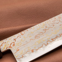 Hayabusa Gyuto Aogami #2 Rainbow Damascus 210 mm je nož za vsestransko uporabo v kuhinji, primeren za meso, ribe in zelenjavo. Tanko rezilo je narejeno iz Aogami #2 jekla, znanega po dolgem ohranjanju ostrine in lahkosti brušenja. Ima unikaten barvit damaščanski vzorec, izdelan s plastenjem medenine in bakra.