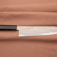 Hayabusa Gyuto Aogami #2 Rainbow Damascus 210 mm je nož za vsestransko uporabo v kuhinji, primeren za meso, ribe in zelenjavo. Tanko rezilo je narejeno iz Aogami #2 jekla, znanega po dolgem ohranjanju ostrine in lahkosti brušenja. Ima unikaten barvit damaščanski vzorec, izdelan s plastenjem medenine in bakra.