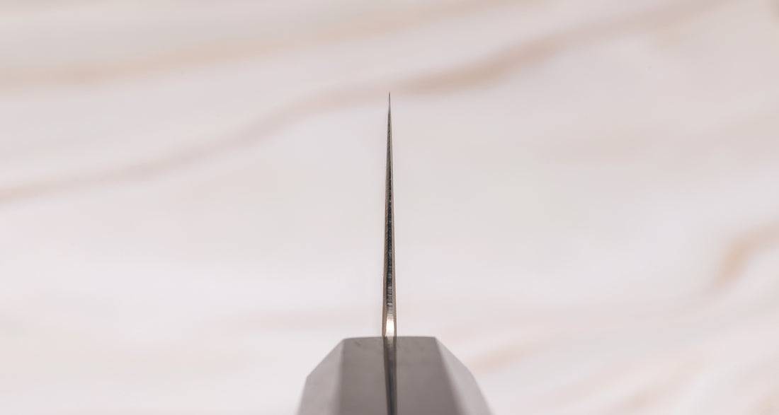 Hayabusa Gyuto Aogami #2 Rainbow Damascus 210 mm je nož za vsestransko uporabo v kuhinji, primeren za meso, ribe in zelenjavo. Tanko rezilo je narejeno iz Aogami #2 jekla, znanega po dolgem ohranjanju ostrine in lahkosti brušenja. Ima unikaten barvit damaščanski vzorec, izdelan s plastenjem medenine in bakra.