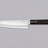 Kawamura Santoku Damascus je vsestranski japonski kuhinjski nož, ročno kovan in laminiran po metodi san-mai. Sredica je izdelana iz jekla AUS-10 in ovita v plasti damaščanskega jekla, zgornji del pa rezila krasijo odtisi kladiva. Japonski ročaj je izdelan iz žganega kostanjevega lesa z obročkom iz bivoljega roga.