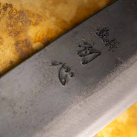 Detajl Kokugei Santoku Aogami #1 Kuro-uchi Ebony 165 mm, ki prikazuje kuro-uchi površinsko obdelavo rezila in kanji pismenke.