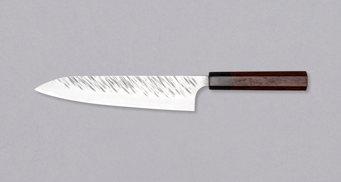 Kurosaki Gyuto Fujin je še eno unikatno rezilo iz rok nadarjenega kovaškega mojstra Yu Kurosakija. Fujin je japonski bog vetra in en najstarejših bogov šintoizma, zato črte na rezilu spominjajo na sunke viharja. Rezilo je izdelano iz SG2 prašnega jekla in ima ročaj iz palisandra s pakka obročkom. Zbirateljski kos!