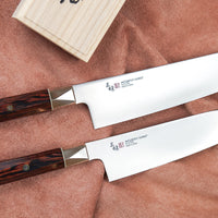 Mcusta Zanmai Supreme Twisted set nožev vsebuje dva vsestranska japonska noža santoku in gyuto. Noža imata minimalistično monosteel rezilo iz VG-10 jekla in unikatni ročaj zavite osemkotne oblike iz edinstvenega in vzdržljivega rdečega pakka lesa, okrašen z mozaično zakovico.