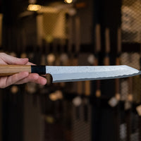 Nigara Kurozome Kiritsuke Yanagiba Aogami #2 Damascus 240 mm je tradicionalni japonski nož, ki se uporablja za pripravo rib (zlasti za sashimi in nigiri sushi). Dolgo rezilo omogoča lepe in dolge gibe, prirezana konica pa natančen zaključek reza.