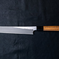 Nigara Kurozome Kiritsuke Yanagiba Aogami #2 Damascus 240 mm je tradicionalni japonski nož, ki se uporablja za pripravo rib (zlasti za sashimi in nigiri sushi). Dolgo rezilo omogoča lepe in dolge gibe, prirezana konica pa natančen zaključek reza.