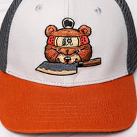 OsterRob ekskluziven merch: OsterRob x Vincent Trinidad kapa Ekskluziven OsterRob dizajn rjavega medveda sumoborca, oboroženega z našim ZDP-189 Bunka Black japonskim nožem, ki je plod sodelovanja z umetnikom Vincentom Trinidadom. Na spodnjem delu vizirja kape je logotip SharpEdge, ki krasi japonsko vzhajajoče sonce.