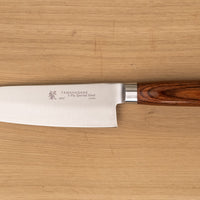 Tamahagane "SAN" Santoku 160 mm - Rezilo je kovano iz jekla VG-5 z visokim odstotkom ogljika, molibdenom in vanadijem ter z izjemno trdoto 61 HRC, rezalni rob je ročno brušen pod kotom med 14 in 15˚. Nož združuje popolno uravnoteženost med ostrino in trdnostjo, zato je primerno tudi za profesionalno delovno okolje.
