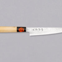Tanaka Petty Aogami #2 Damascus 150mm je odlična izbira za vse kuharje, ki želijo ročno kovan japonski nož iz tradicionalnega jekla s pravo japonsko fino ostrino. Nož z minimalističnim zaključnim videzom na rezilu in klasičnim wa ročajem iz lesa magnolije pooseblja japonsko estetiko. Pride v paulownia leseni škatlici.