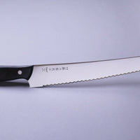 Tojiro Pankiri (nož za kruh) 270 mm_2 Ročno kovan nož za kruh z daljšim 270mm rezilom je nepogrešljiv pripomoček poklicnega ali domačega kuharja, ki se veliko ukvarja s peko kruha in peciva. Rezilo je obdelano do visokega sijaja (migaki). Odlično nerjaveče MV jeklo je kovano do trdote 57–59 HRC. Rezilo je neobčutljivo na zunanje dejavnike in zelo ostro.