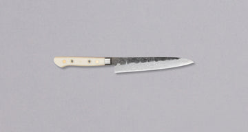 Mali vsestranski japonski nož za manjša in ročna opravila. Rezilo je ročno kovano do popolnosti z lasersko natančnostjo, za rustikalen videz so dodani udarci s kladivom, nerjaveče jeklo VG-10 je kaljeno na 61HRC, kanji pa ročno izklesan v delavnici Tojiro Atelier. Yo ročaj je iz trpežne micarte v kremasto beli barvi.
