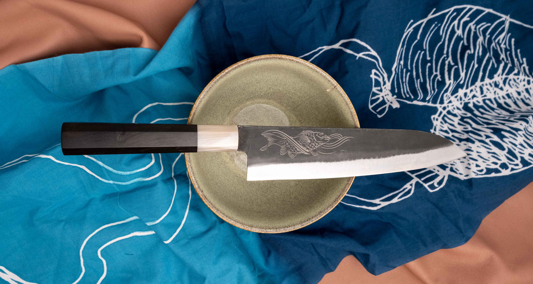 Yoshida Gyuto SUJ-2 Kuro-uchi 210 mm je ročno izdelan srednje velik kuhinjski nož, popoln za različna opravila v kuhinji. Kuro-uchi serija Yoshida Hamono združuje trpežno SUJ-2 jeklo (64,7 HRC) za izjemno obstojnost ostrine in kuro-uchi zaključek, ki zagotavlja rustikalen videz in dodatno zaščito rezila. Ročaj iz ebenovine omogoča varen oprijem in natančen nadzor pri rezanju. 