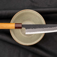 Japonski nož Hokiyama Bunka Aogami Super Kuro-uchi 170 mm je večnamenski nož iz Aogami Super jekla, ki dolgo časa drži ostrino. Kuro-uchi patina ga ščiti pred korozijo, odtisi kladiv pa preprečujejo lepljenje hrane na rezilo. Ima tradicionalni japonski wa ročaj oktagonalne oblike iz mahagonija in zelkovega lesa.