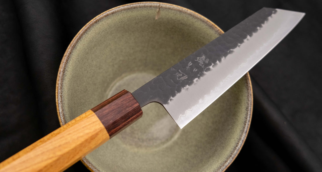 Japonski nož Hokiyama Bunka Aogami Super Kuro-uchi 170 mm je večnamenski nož iz Aogami Super jekla, ki dolgo časa drži ostrino. Kuro-uchi patina ga ščiti pred korozijo, odtisi kladiv pa preprečujejo lepljenje hrane na rezilo. Ima tradicionalni japonski wa ročaj oktagonalne oblike iz mahagonija in zelkovega lesa.