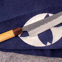 Japonski nož Hokiyama Bunka Aogami Super Kuro-uchi 170 mm je večnamenski nož iz Aogami Super jekla, ki dolgo časa drži ostrino. Kuro-uchi patina ga ščiti pred korozijo, odtisi kladiv pa preprečujejo lepljenje hrane na rezilo. Ima tradicionalni japonski wa ročaj oktagonalne oblike iz mahagonija in zelkovega lesa.