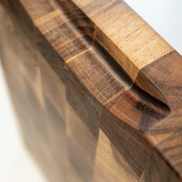 Ročno izdelana kuhinjska deska za rezanje je narejena iz orehovega lesa. Posebnost te deske je, da je sestavljena tako, da so vlakna lesa obrnjena navzgor in zato nudi boljše pogoje za rezanje, saj takšna podlaga manj poškoduje rezalno površino noža. V kompletu z desko je tudi olje za nego in zaščito lesenih površin. Na sliki: Rob rezalne deske, prilagojen za oprijem z dlanmi.