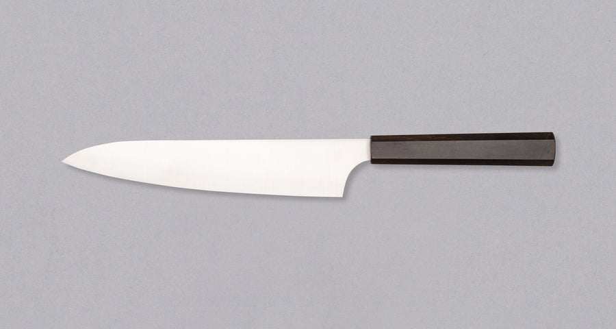 Nož Hayabusa Gyuto Aogami Super 210 mm je prava izbira za ljubitelje japonskih kuhinjskih mojstrovin. Gyuto oblika rezila zagotavlja vsestranskost pri rezanju mesa, zelenjave in rib, zato je odličen pripomoček za različne rezalne tehnike. Rezilo iz visokokakovostnega Aogami Super jekla s trdoto 63 HRC ohranja izjemno ostrino in natančnost, hkrati pa ima čudovit migaki videz in edinstvene japonske pismenke, ki poudarjajo tradicijo in slog. Osemkotni ročaj iz temne ebenovine nudi stabilen in udoben oprijem za