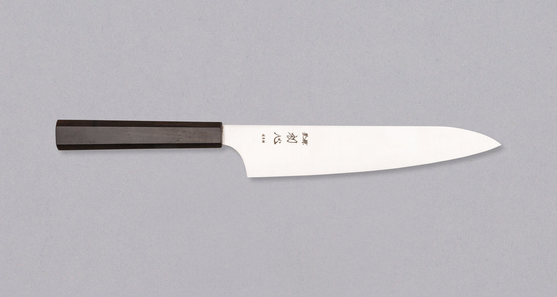 Nož Hayabusa Gyuto Aogami Super 210 mm je prava izbira za ljubitelje japonskih kuhinjskih mojstrovin. Gyuto oblika rezila zagotavlja vsestranskost pri rezanju mesa, zelenjave in rib, zato je odličen pripomoček za različne rezalne tehnike. Rezilo iz visokokakovostnega Aogami Super jekla s trdoto 63 HRC ohranja izjemno ostrino in natančnost, hkrati pa ima čudovit migaki videz in edinstvene japonske pismenke, ki poudarjajo tradicijo in slog. Osemkotni ročaj iz temne ebenovine nudi stabilen in udoben oprijem za