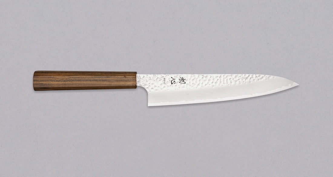 Hayabusa Gyuto VG-10 Tsuhime Bubinga 210 mm je vsestranski nož, ki je primeren za uporabo v domači in profesionalni kuhinji. Tanko in natančno rezilo iz vrhunskega VG-10 jekla omogoča enostavno delo tudi z drobnimi sestavinami. Nož izstopa s prefinjenim videzom: migaki rezilo krasi droben vzorec kladiva, medtem ko izrazita valovita linija ločuje plasti jekla in jedro, ustvarjajoč kontrast med matirano in sijočo površino.