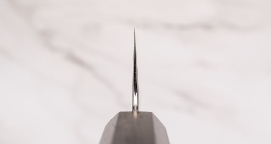 Hayabusa Gyuto VG-10 Tsuhime Bubinga 210 mm je vsestranski nož, ki je primeren za uporabo v domači in profesionalni kuhinji. Tanko in natančno rezilo iz vrhunskega VG-10 jekla omogoča enostavno delo tudi z drobnimi sestavinami. Nož izstopa s prefinjenim videzom: migaki rezilo krasi droben vzorec kladiva, medtem ko izrazita valovita linija ločuje plasti jekla in jedro, ustvarjajoč kontrast med matirano in sijočo površino.