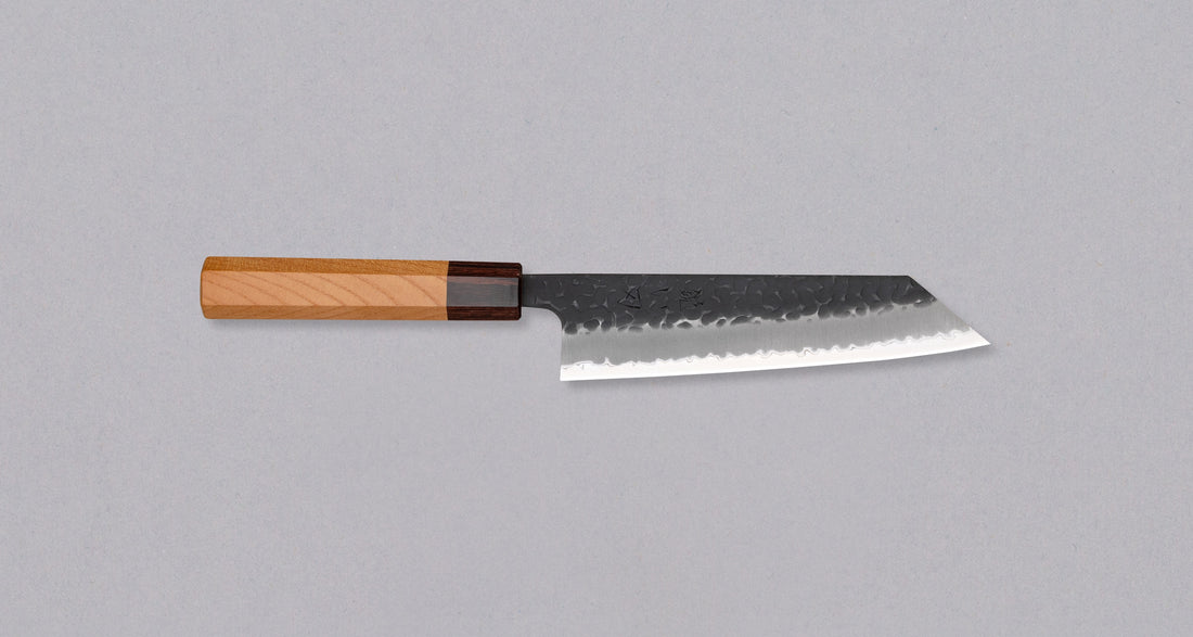 Japonski nož Hokiyama Bunka Aogami Super Kuro-uchi 170 mm je večnamenski nož iz Aogami Super jekla, ki dolgo časa drži ostrino. Kuro-uchi patina ga ščiti pred korozijo, odtisi kladiv pa preprečujejo lepljenje hrane na rezilo. Ima tradicionalni japonski wa ročaj oktagonalne oblike iz mahagonija in zelkovega lesa.