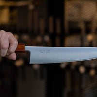 Nož Hokiyama Gyuto SRS13 Migaki 210 mm je odlična izbira za vse profesionalne kuharje in kuharje po duši, ki imajo radi rezila, ki dolgo držijo ostrino, so izjemno ostri, hkrati pa niso zahtevni za vzdrževanje. Tradicionalno japonsko minimalističen videz rezila odlično dopolnjuje eleganten hrastov ročaj Urushi Flame.