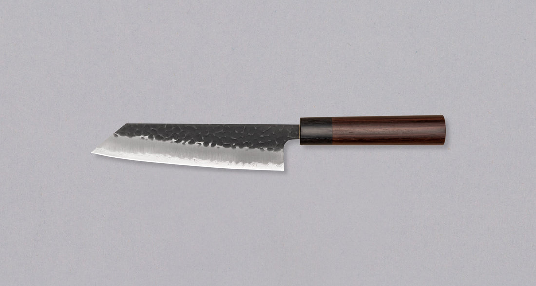 Rezilo Hokiyama Bunka Aogami Super Kuro-uchi 170 mm je odlična izbira za vse, ki si želijo srednje velik večnamenski nož za pripravo mesa, rib in zelenjave, ki dolgo časa drži ostrino. Črna kuro-uchi patina na rezilu ga ščiti pred korozijo, odtisi kladiv pa ustvarjajo zračne žepke, ki preprečujejo lepljenje hrane na rezilo med uporabo. Jedro je iz odličnega Aogami Super jekla.