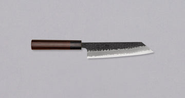 Rezilo Hokiyama Bunka Aogami Super Kuro-uchi 170 mm je odlična izbira za vse, ki si želijo srednje velik večnamenski nož za pripravo mesa, rib in zelenjave, ki dolgo časa drži ostrino. Črna kuro-uchi patina na rezilu ga ščiti pred korozijo, odtisi kladiv pa ustvarjajo zračne žepke, ki preprečujejo lepljenje hrane na rezilo med uporabo. Jedro je iz odličnega Aogami Super jekla.