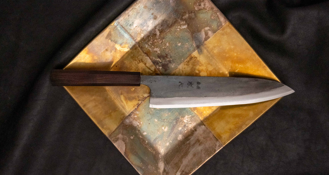 Kokugei Gyuto Aogami #1 Kuro-uchi Ebony 210 mm prikazan z leve strani, z vidnim kuro-uchi zaključkom in elegantnim ročajem iz ebenovine.