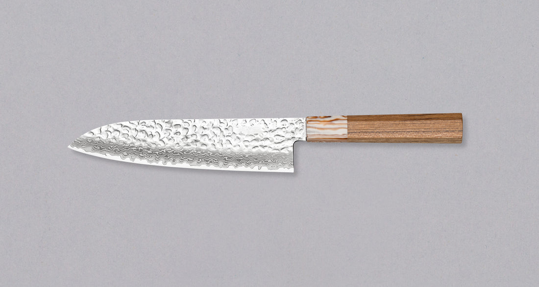 Kotetsu Santoku VG-10 Damascus 180 mm je velik vsestranski nož z vidnimi odtisi kladiv, damascus vzorcem in klasičnim japonskim ročajem (wa-style) iz tikovine. Je izjemno tanek (1,7 mm), zato bo zlahka zdrsel skozi sestavine, nerjaveče VG-10 jeklo pa zagotavlja odpornost na rjo, trpežnost in odpornost proti obrabi.