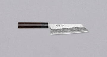 Muneishi Bunka Aogami #2 Damascus 165 mm je vsestranski japonski kuhinjski nož, namenjen za pripravo mesa, rib in zelenjave. Ta nož se drži tradicije, a jo tudi nadgrajuje: oblika bunka, visokoogljično jeklo Aogami #2, udoben ovalni ročaj iz palisandra. Prehod iz migaki v megličast damask vzorec daje pridih elegance.