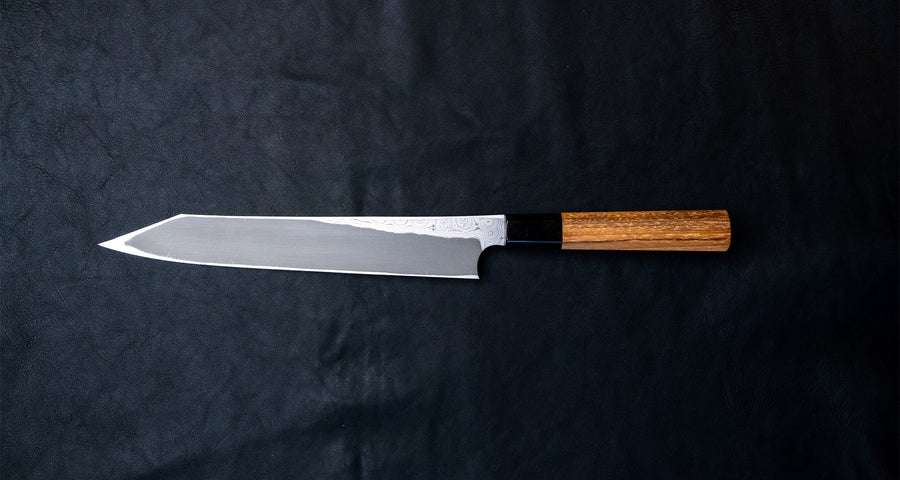 Nigara Kurozome Kiritsuke Yanagiba Aogami #2 Damascus 240 mm je tradicionalni japonski nož, ki se uporablja za pripravo rib (zlasti za sashimi in nigiri sushi). Dolgo rezilo omogoča lepe in dolge gibe, prirezana konica pa natančen zaključek reza.