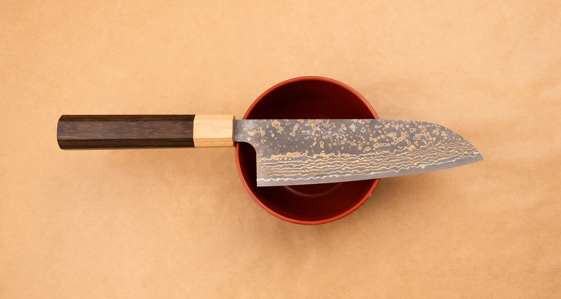 Saji Santoku VG-10 Gold RWO 165 mm je vsestranski japonski kuhinjski nož, primeren za pripravo mesa, rib in zelenjave. Vendar bi mu delali krivico, če bi ga imenovali samo kuhinjski nož, saj je resnično izjemen primerek japonske kovaške spretnosti, od njegovega videza in vse do specifičnih detajlov.