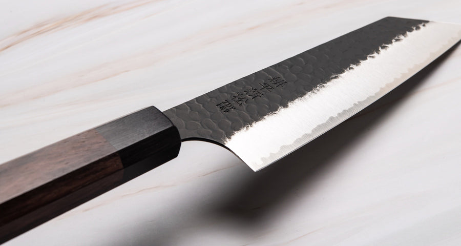 Kouhei-Shinmatsu ZDP-189 Bunka Black 200 mm je plod desetletja izkušenj, nabranih s prodajo in dela z noži z naše strani in znanja kovanja nožev mojstrov kovačije Suncraft. Skupaj s črnim kuro-uchi zaključkom, obdelanim z udarci kladiva, in elegantnim osemkotnim ročajem iz palisandra, je ta nož zmagovalna kombinacija!