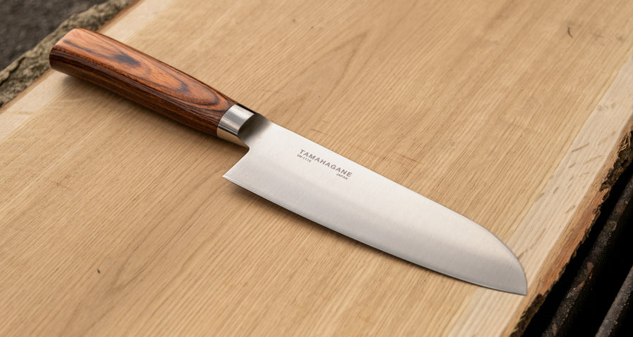 Tamahagane "SAN" Santoku 160 mm - Rezilo je kovano&nbsp;iz jekla&nbsp;VG-5 z visokim odstotkom ogljika, molibdenom in vanadijem ter z izjemno&nbsp; trdoto 61 HRC, rezalni rob&nbsp;je ročno brušen pod kotom med 14 in 15˚.&nbsp;Nož&nbsp;združuje popolno uravnoteženost med ostrino in trdnostjo, zato je primerno tudi&nbsp;za profesionalno delovno okolje.