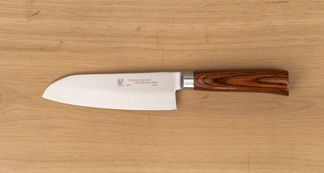 Tamahagane "SAN" Santoku 160 mm - Rezilo je kovano&nbsp;iz jekla&nbsp;VG-5 z visokim odstotkom ogljika, molibdenom in vanadijem ter z izjemno&nbsp; trdoto 61 HRC, rezalni rob&nbsp;je ročno brušen pod kotom med 14 in 15˚.&nbsp;Nož&nbsp;združuje popolno uravnoteženost med ostrino in trdnostjo, zato je primerno tudi&nbsp;za profesionalno delovno okolje.