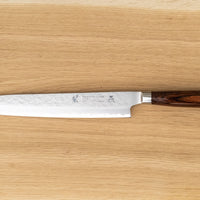 Tamahagane "TSUBAME" Sashimi-Slicer 240mm je izdelan iz VG-5 nerjavečega jekla in ima zelo vzdržljiv in vodoodporen ročaj iz pakka lesa. Izjemno nezahteven in zanesljiv nož, primeren za profesionalne kuharje.