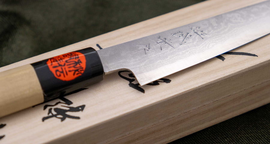 Tanaka Petty Aogami #2 Damascus 150mm je odlična izbira za vse kuharje, ki želijo ročno kovan japonski nož iz tradicionalnega jekla s pravo japonsko fino ostrino. Nož z minimalističnim zaključnim videzom na rezilu in klasičnim wa ročajem iz lesa magnolije pooseblja japonsko estetiko.  Pride v paulownia leseni škatlici.