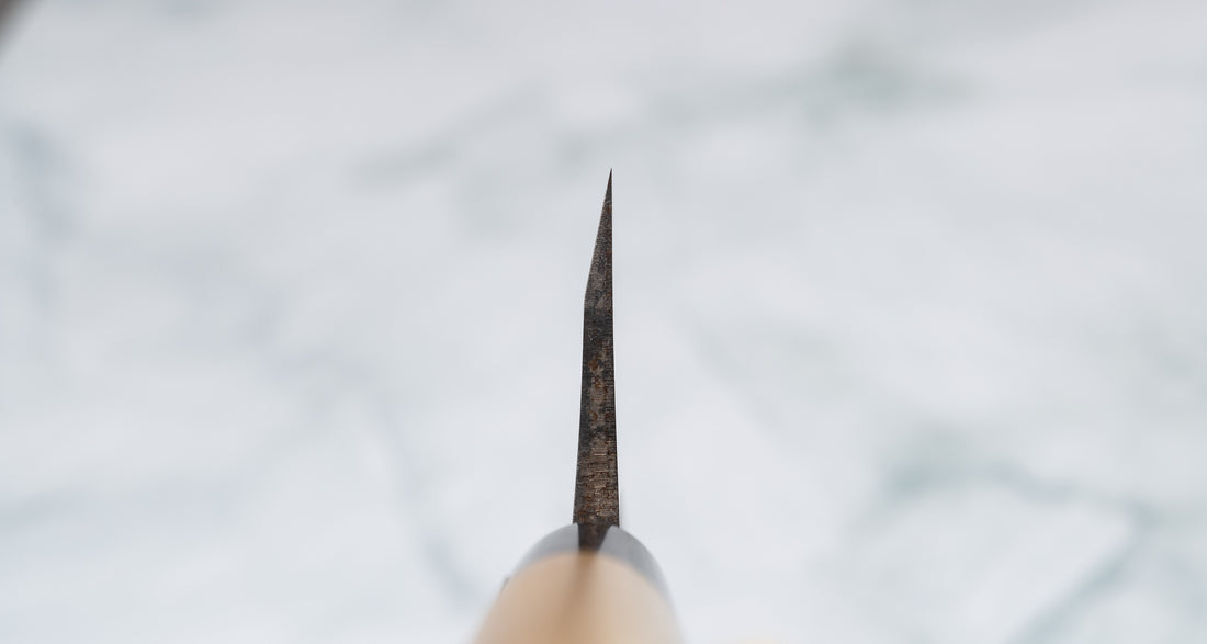 Japonski kuhinjski nož deba, primeren za celovito pripravo srednje velikih rib in perutnine z manjšimi kostmi. Na sliki je "choil" oziroma profil rezila, ki je oblike hamaguri in je enostransko brušen, zato primeren samo za desničarje. Nož je izdelan iz Shirogami jekla v kovačiji Tojiro na Japonskem. Ročaj je D-oblike, iz lesa magnolije z obročkom iz roga vodnega bivola. Kupite zdaj na osterrob.si.