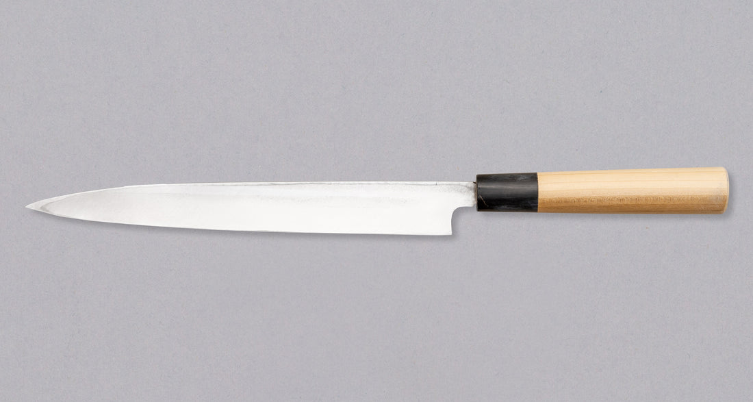Nož Yanagiba 240 mm priznanega proizvajalca Tojiro, ki ga zaznamuje japonski magnolijin ročaj z obročkom roga vodnega bivola, minimalistično oblikovano rezilo in vrhunsko Shirogami #1 jeklo. Rezultat je lahek, oster, vsestranski kuhinjski nož za domače in poklicne kuharje z rezilom, ki dolgo drži ostrino in se enostavno ponovno nabrusi.