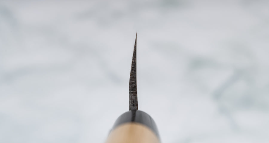 Nož Yanagiba 240 mm priznanega proizvajalca Tojiro, ki ga zaznamuje japonski magnolijin ročaj z obročkom roga vodnega bivola, minimalistično oblikovano rezilo in vrhunsko Shirogami #1 jeklo. Rezultat je lahek, oster, vsestranski kuhinjski nož za domače in poklicne kuharje z rezilom, ki dolgo drži ostrino in se enostavno ponovno nabrusi. Na sliki: choil Yanagibe.
