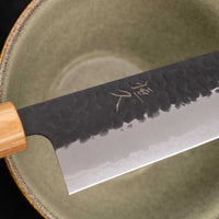 Tsunehisa Kiritsuke AS Kuro-uchi 240 mm je japonski nož, ki ga poleg enega najboljših jekel za kuhinjske nože in popolnega profila rezila (zelo tanko rezilo!), zaznamuje tudi unikatna kombinacija temne patine in odtisov kladiva, ki ju vizualno lepo dopolnjuje klasičen japonski ročaj iz palisandra in javorjevega lesa.