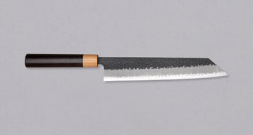 Tsunehisa Kiritsuke AS Kuro-uchi 240 mm je japonski nož, ki ga poleg enega najboljših jekel za kuhinjske nože in popolnega profila rezila (zelo tanko rezilo!), zaznamuje tudi unikatna kombinacija temne patine in odtisov kladiva, ki ju vizualno lepo dopolnjuje klasičen japonski ročaj iz palisandra in javorjevega lesa.