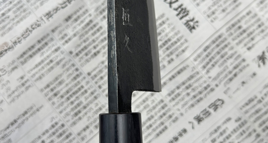 Tsunehisa Ryo-Deba Aogami #2 Kurouchi 165 mm je tradicionalni japonski kuhinjski nož, specializiran za pripravo rib in mesa. Ker je brušena dvostrano, jo je lažje brusiti, hkrati pa je idealna za bolj groba rezalna opravila, kot je rezanje kosti velikih rib in piščancev. Ima tradicionalni japonski ročaj iz palisandra.