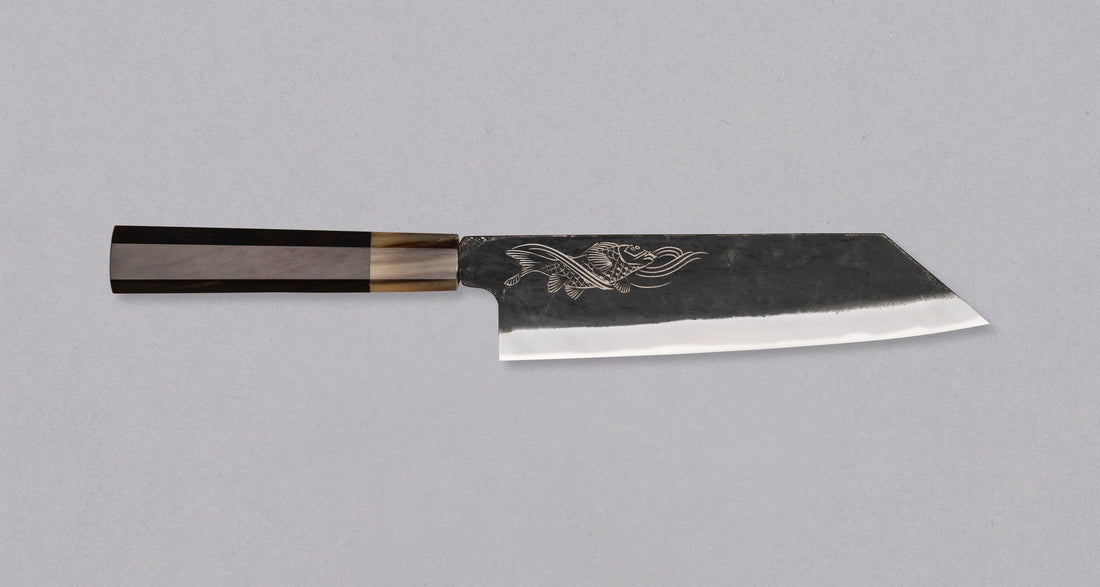 Yoshida Bunka SUJ-2 Kuro-uchi 190 mm ročno izdelan kuhinjski nož iz serije Yoshida Hamono, s trpežnim SUJ-2 jeklom, rustikalnim kuro-uchi zaključkom, ročajem iz ebenovine ter unikatno gravuro koi krapa, idealen za raznolika kuhinjska opravila in kot darilo.