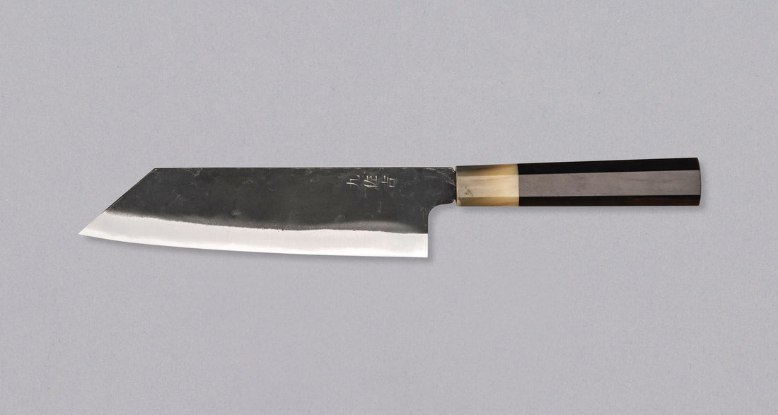 Yoshida Bunka SUJ-2 Kuro-uchi 190 mm ročno izdelan kuhinjski nož iz serije Yoshida Hamono, s trpežnim SUJ-2 jeklom, rustikalnim kuro-uchi zaključkom, ročajem iz ebenovine ter unikatno gravuro koi krapa, idealen za raznolika kuhinjska opravila in kot darilo.