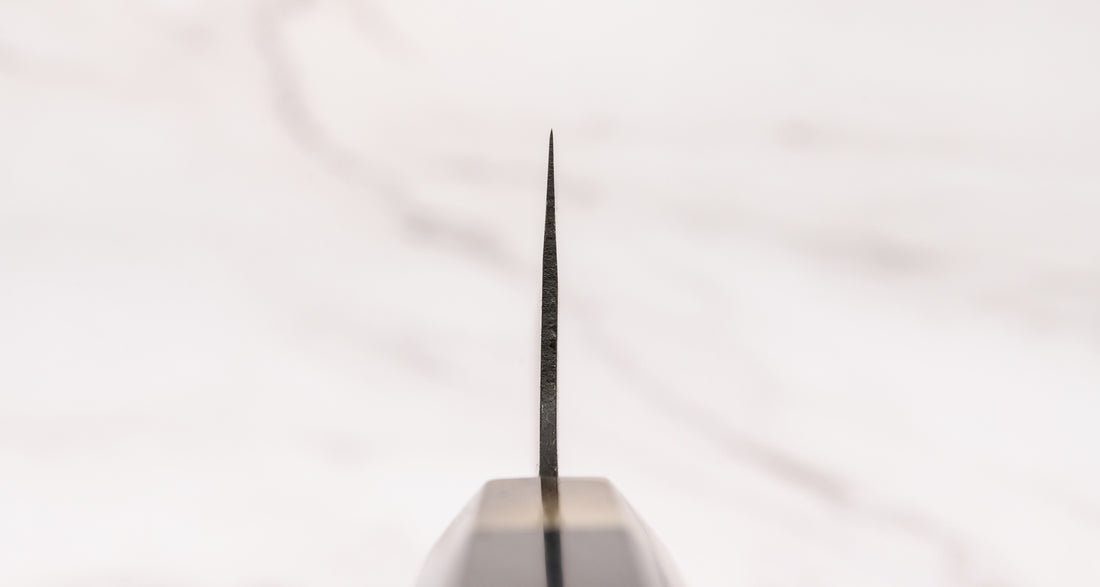 Yoshida Bunka SUJ-2 Kuro-uchi 190 mm ročno izdelan kuhinjski nož iz serije Yoshida Hamono, s trpežnim SUJ-2 jeklom, rustikalnim kuro-uchi zaključkom, ročajem iz ebenovine ter unikatno gravuro koi krapa, idealen za raznolika kuhinjska opravila in kot darilo.