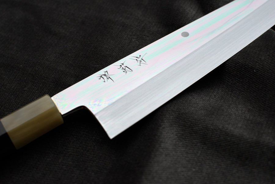 Kawamura Mizu-Honyaki Gyuto je ročno kovan nož, izdelan z neverjetno natančnostjo, ki je plod stoletja izkušenj in učenja. Gre za preplet odličnega delovnega orodja in umetniškega dela. Honyaki se lahko prevede kot “resnično kovan” in ta način kovanja je najčistejši odraz tradicionalne japonske umetnosti izdelave mečev. 